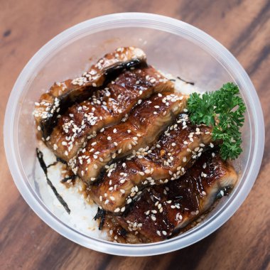 Unagi Don plastik bir kaseye susam serpti. Yemek teslimatı.