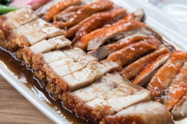 Tahta bir masada sulu, gevrek domuz eti ve kızarmış ördek. Kapat.