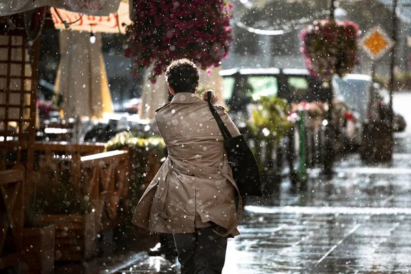 一个穿外套的人在雨中沿街走着 — 图库照片