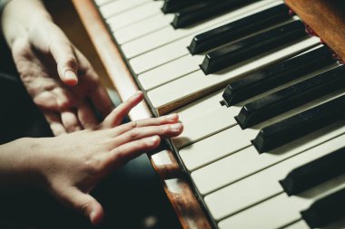 Eller piyano tuşlarında, yakın plan.