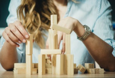 Kız, yakın çekim masasına ahşap tuğlalardan bir kule yığıyor.