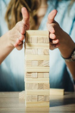 Kız ahşap tuğlalardan bir kule dizer.