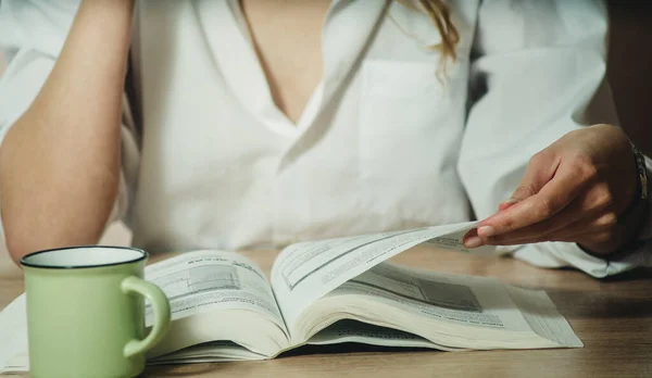 Kız kitap okuyor ve yakın planda kahve içiyor.