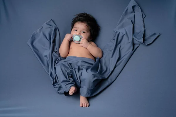 Mavi Şalla Kaplı Yatağa Yaslanmış Emzik Takmış Bir Çocuğun Portresi — Stok fotoğraf