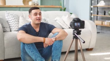 Young male blogger talking on digital camera recording video vlog at home