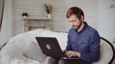 Young man very happy and rejoices using his laptop at home