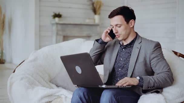 Бизнесмен разговаривает по мобильному телефону и использует ноутбук в офисе — стоковое видео