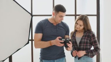 Profesyonel fotoğrafçı stüdyoda çekim sırasında kız modeli için bir dijital fotoğraf makinesinde fotoğraf gösteren