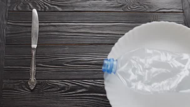 Plastflaska på en tallrik med gaffel och kniv. Plastföroreningar och plastavfall Concept — Stockvideo