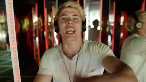 Jeune rappeur homme avec écouteurs chantant émotionnel dans fond néon lumières — Video