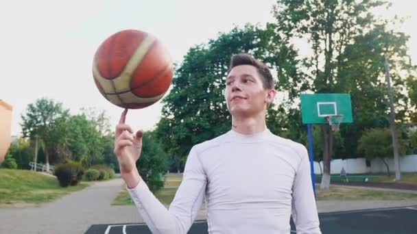 Mladý basketbalista otáčí míč na prstu ve zpomaleném filmu — Stock video