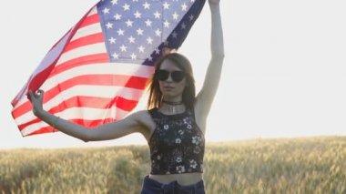 Gün batımında Usa bayrağını ağır çekimde tutan vatansever genç bir kadın. Bağımsızlık Günü kavramı
