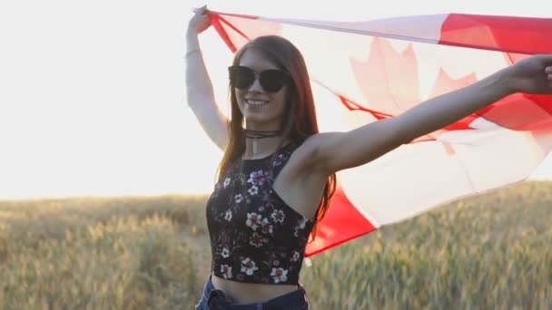 Jovem patriótica segurando bandeira do Canadá ao pôr do sol em câmera lenta . — Vídeo de Stock