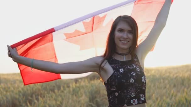 Mujer patriótica joven sosteniendo la bandera de Canadá al atardecer en cámara lenta — Vídeos de Stock