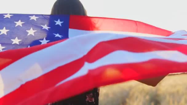Nahaufnahme eines jungen amerikanischen Mädchens, das bei Sonnenuntergang mit der Flagge der Vereinigten Staaten von Amerika läuft. Zeitlupe — Stockvideo