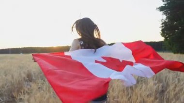 Genç kız gün batımında Kanada bayrağıyla koşuyor ve eğleniyor. Yavaş çekim