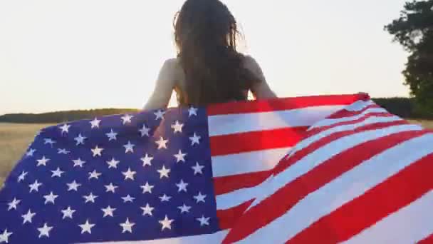 Giovane ragazza americana che corre con la bandiera degli Stati Uniti d'America al tramonto. Concetto di Giorno dell'indipendenza USA — Video Stock