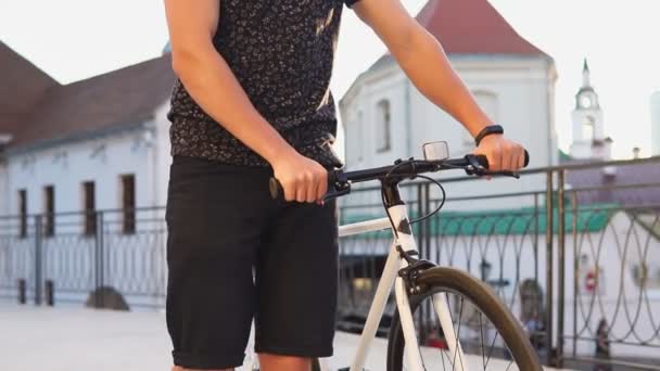 Gros plan des hipsters marchant avec un vélo à engrenages fixes en ville. Mouvement lent — Video