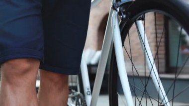 Kentsel arka planda beyaz bir yol bisikleti sürüş rahat adam bisikletçi yakın. Yavaş çekim