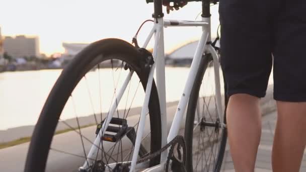 Primer plano de ciclista hombre casual montar una bicicleta de carretera blanca en la calle. Movimiento lento — Vídeos de Stock