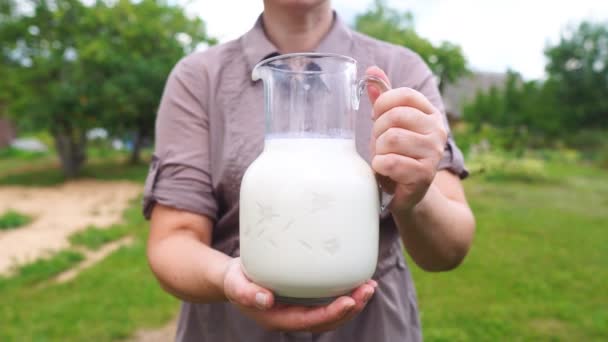 Primer plano de una agricultora sosteniendo una jarra con leche fresca — Vídeos de Stock