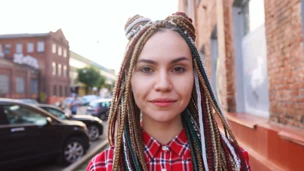 Portret uśmiechniętej modnej nastoletniej dziewczyny z dredy w tle miejskim, powolny ruch — Wideo stockowe