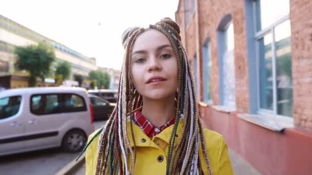 Portrét usmívající se módní dívky s dredy na městském pozadí, pomalý pohyb — Stock video