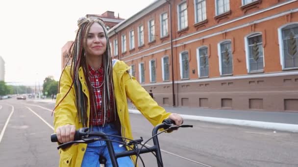Snygg hipster tjej med dreadlocks ridning gul retro cykel i staden — Stockvideo