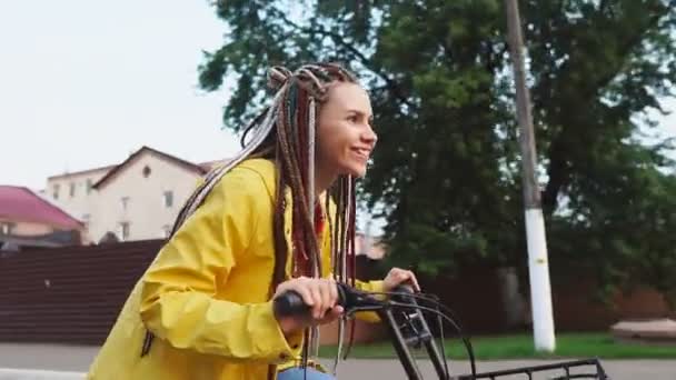 Joven hipster chica con rastas equitación amarillo vintage bicicleta y divertirse — Vídeos de Stock