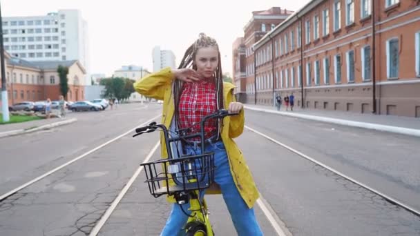 Chica joven con rastas y chaqueta amarilla posando con moto amarilla vintage, cámara lenta — Vídeos de Stock