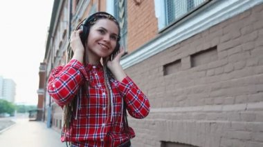 Dreadlocks ile Trendy genç kız kulaklık müzik dinlerken ve sokakta yürüme
