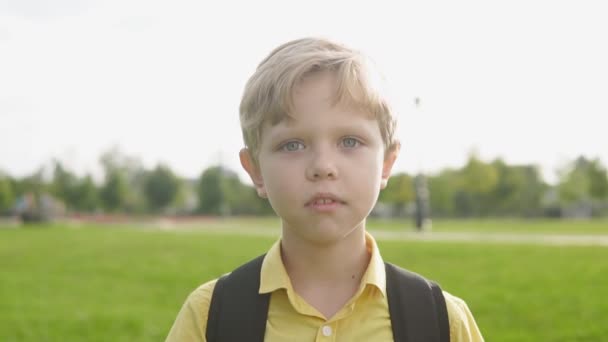 Portret van blonde jongen met vinger wees op. Klein kind met rugzak heeft idee. — Stockvideo