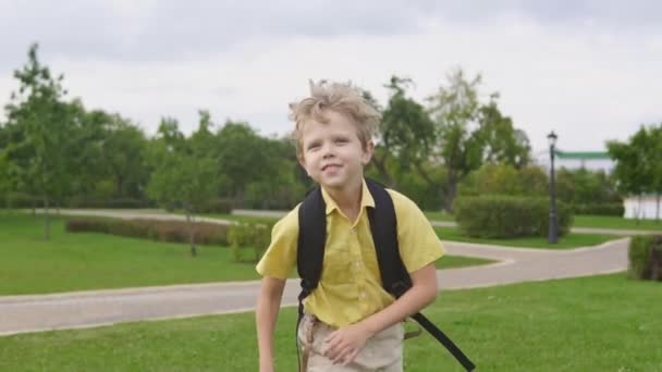 Joyeux garçon blond avec sac à dos courir dans le parc, au ralenti — Video