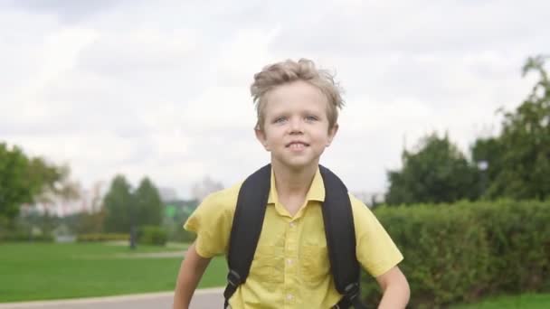 Joyeux petit garçon avec sac à dos dans le parc, au ralenti. Concept de retour à l'école — Video