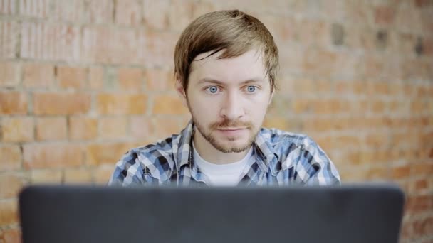 Young man very happy and rejoices sitting in front of laptop — Stock Video