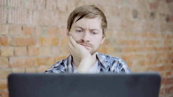 Dizüstü bilgisayarın önünde sıkılan genç adam — Stok video