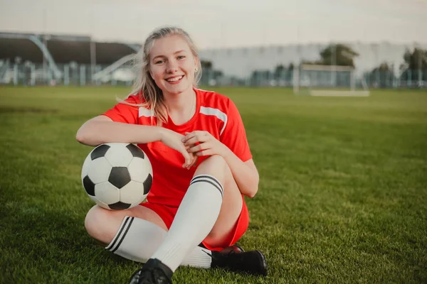 Retrato de jogador de futebol menina sorridente com bola de futebol sentado na grama, espaço de cópia — Fotografia de Stock