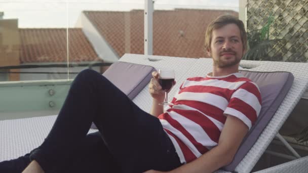 Relaxing young man drinking some red wine at a rooftop — Stock Video