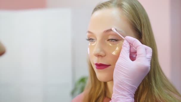 Визажист наносит макияж на брови в салоне красоты, закрывается — стоковое видео
