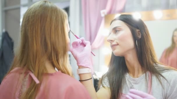 Artista de maquillaje profesional trabajando en cejas modelo en un salón de belleza — Vídeos de Stock