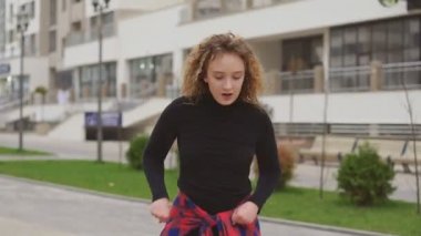 Şehirli arka planında afro saç stili, modern hip-hop dansı yapan neşeli genç kız.