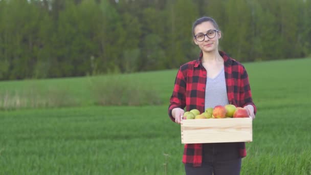 Retrato de una agricultora sonriente sosteniendo una caja de fruta recién cosechada, espacio para copiar — Vídeos de Stock