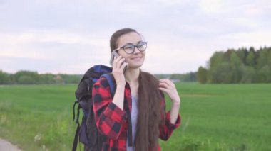 Genç bayan otostopçu aile ile iletişim kurmak için akıllı telefondan konuşuyor..