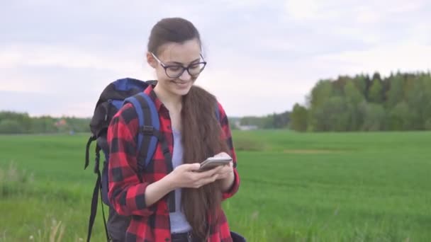 Exitosa joven excursionista utilizando el teléfono inteligente para comunicarse con la familia. Concepto de viaje y senderismo — Vídeo de stock