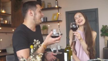 Mutlu tutkulu çift evde romantik bir akşam yemeği yiyor, şarap içiyor, yavaş çekimde.