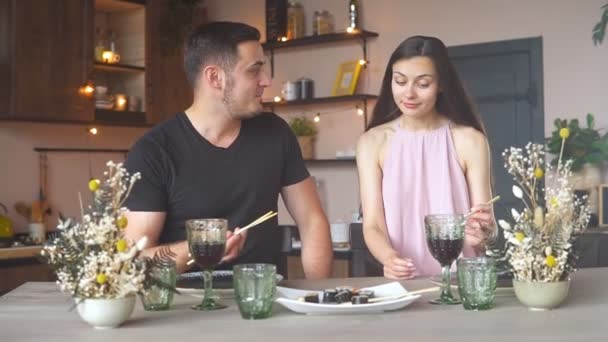 Felice coppia appassionata mangiare sushi e bere vino rosso da bicchieri, mentre avendo cena romantica a casa, rallentatore — Video Stock