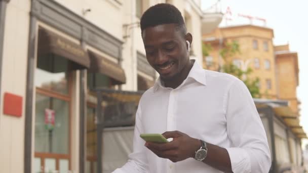 Porträt eines jungen afrikanisch-amerikanischen Geschäftsmannes im weißen Hemd mit Smartphone in der Stadt — Stockvideo