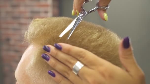 Gros plan d'une jeune coiffeuse professionnelle faisant une coupe de cheveux pour son client. — Video