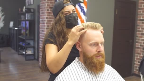 在现代理发店里，年轻的姜人正在理新发。戴面具为客户理发的年轻专业理发师. — 图库视频影像