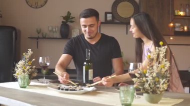 Mutlu tutkulu çift suşi yiyor ve bardaktan kırmızı şarap içiyor.
